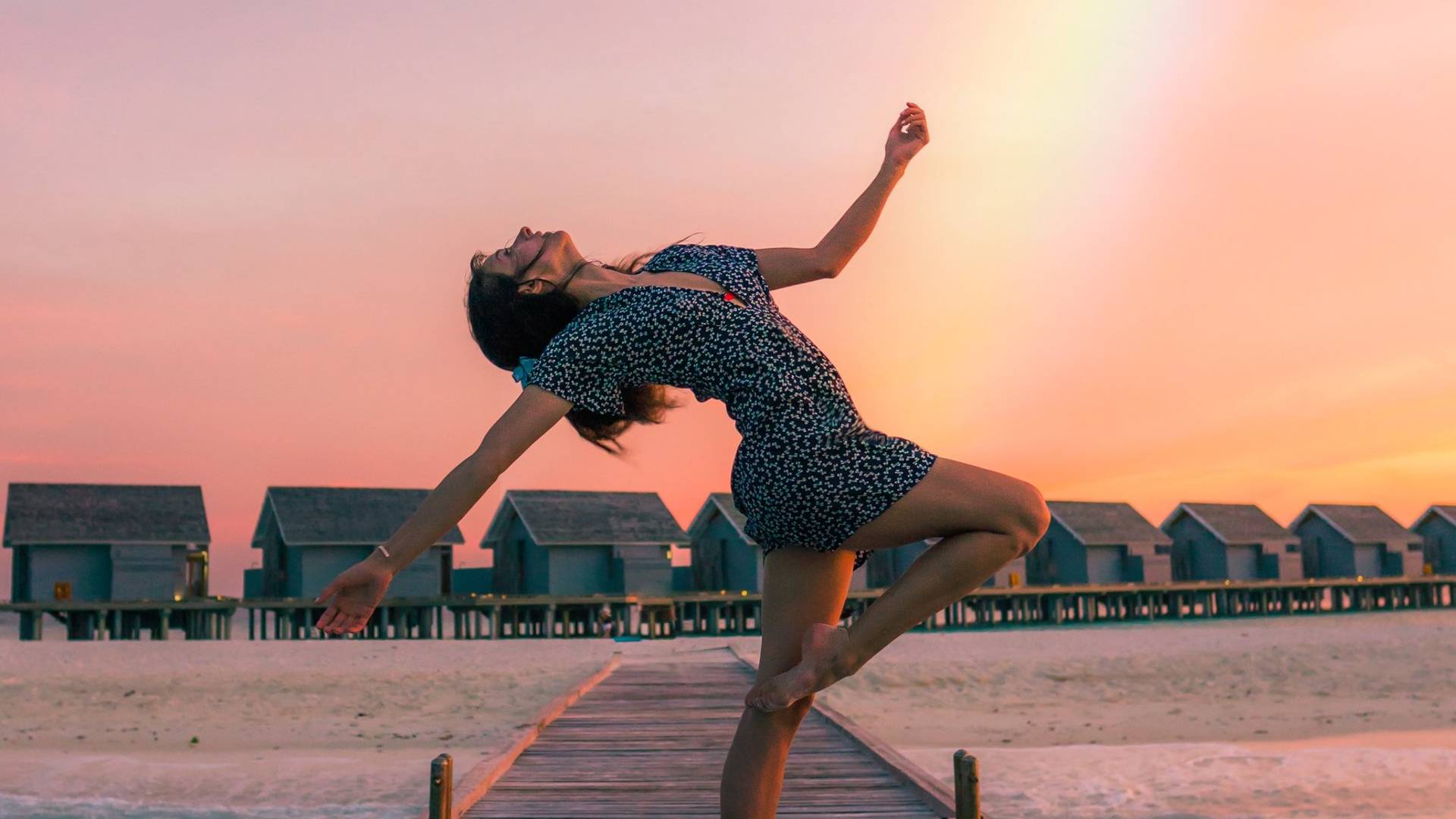 Girl dancing with a beautiful view on the ocean and rainbow in the sky